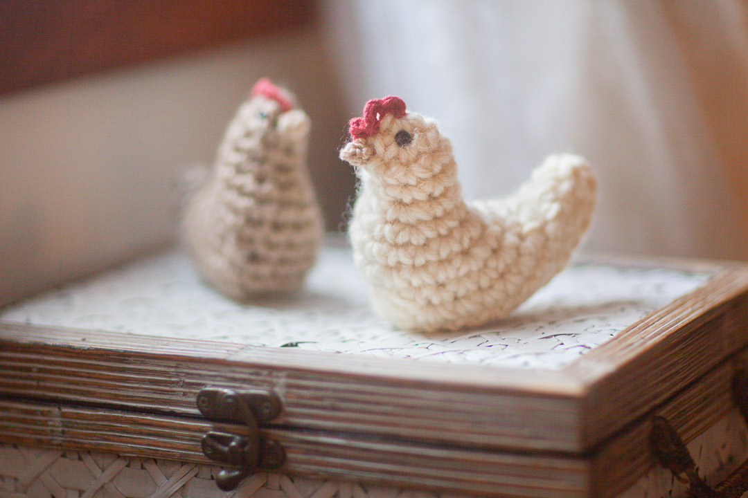two chunky crochet chickens placed on a basket, made with large yarn