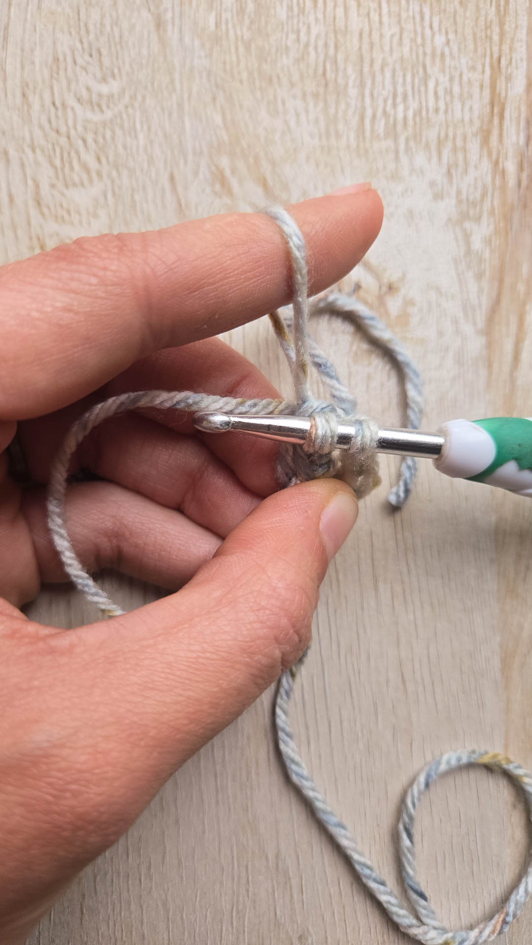 Hand holding crochet hook and yarn