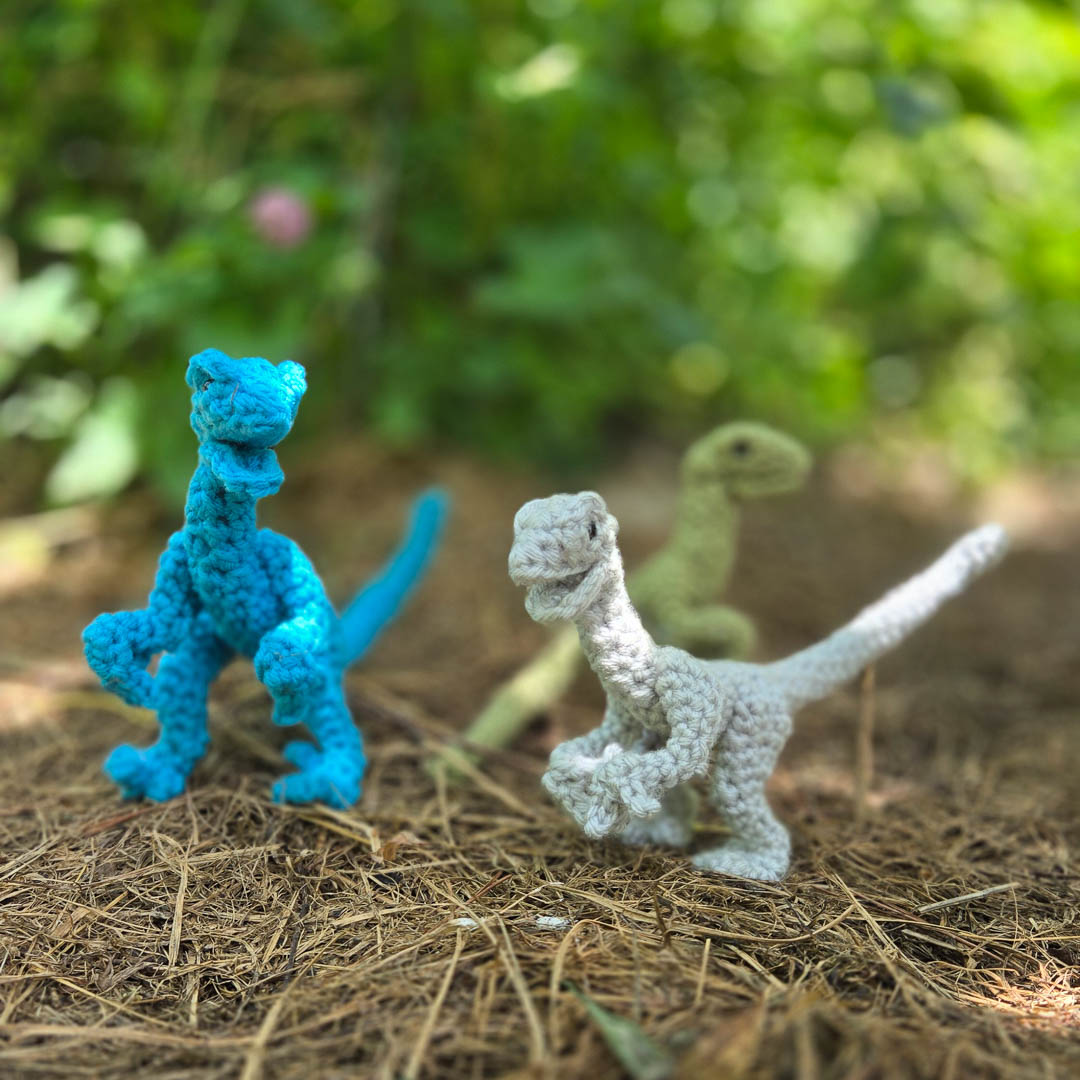 Three crochet dinosaurs staring at you.
