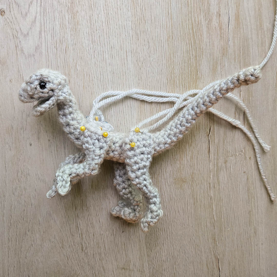 A crochet dinosaur being pinned together.
