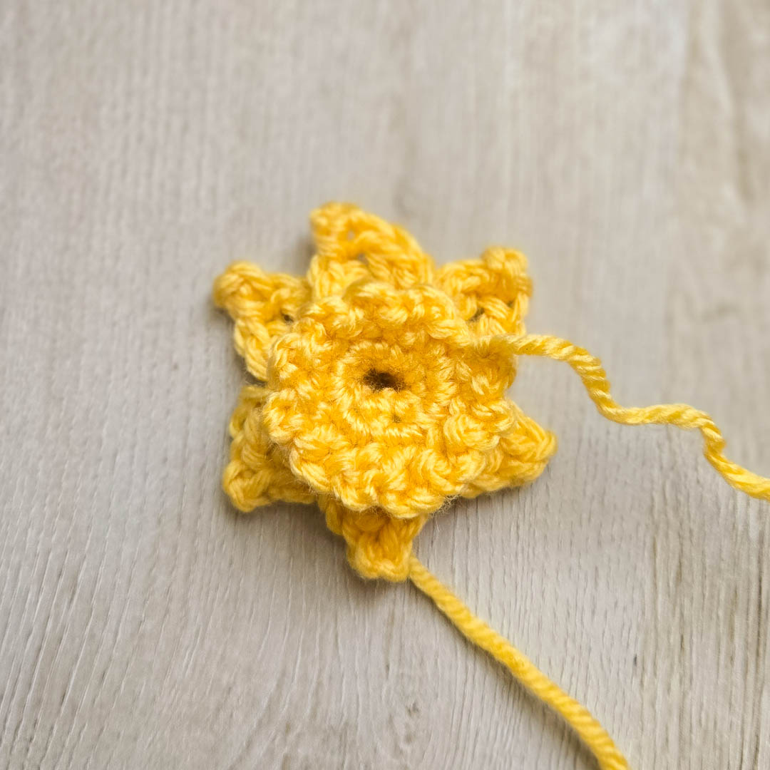 a pair of crochet pumpkins sitting in front of a decorative wooden lantern