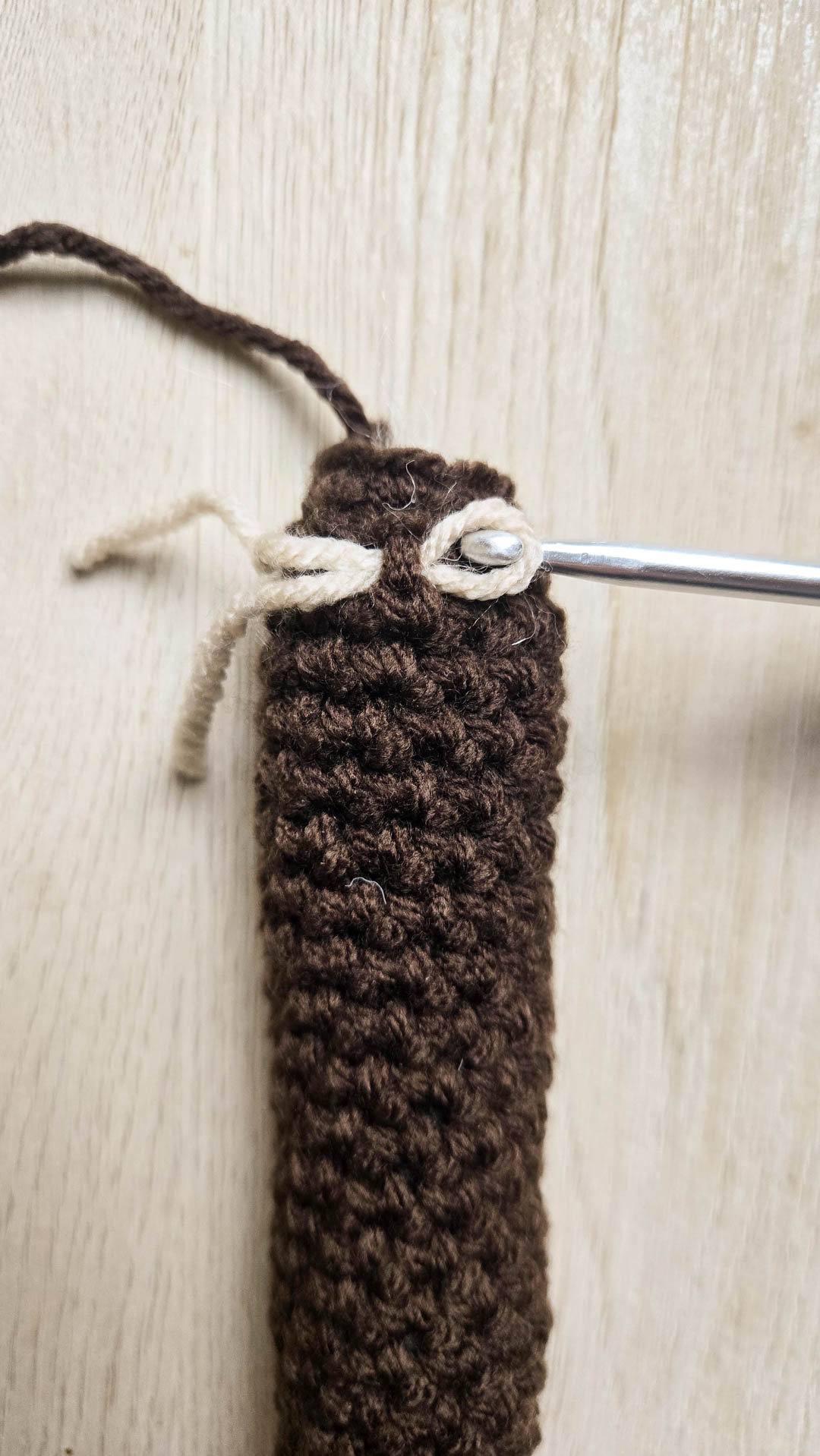 A short thread being drawn through a crochet stitch.