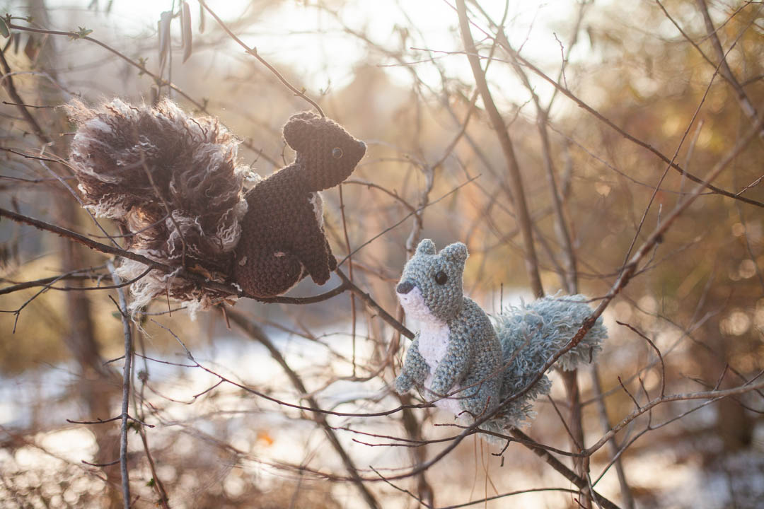 Two crochet squirrels in the branches of a tree.