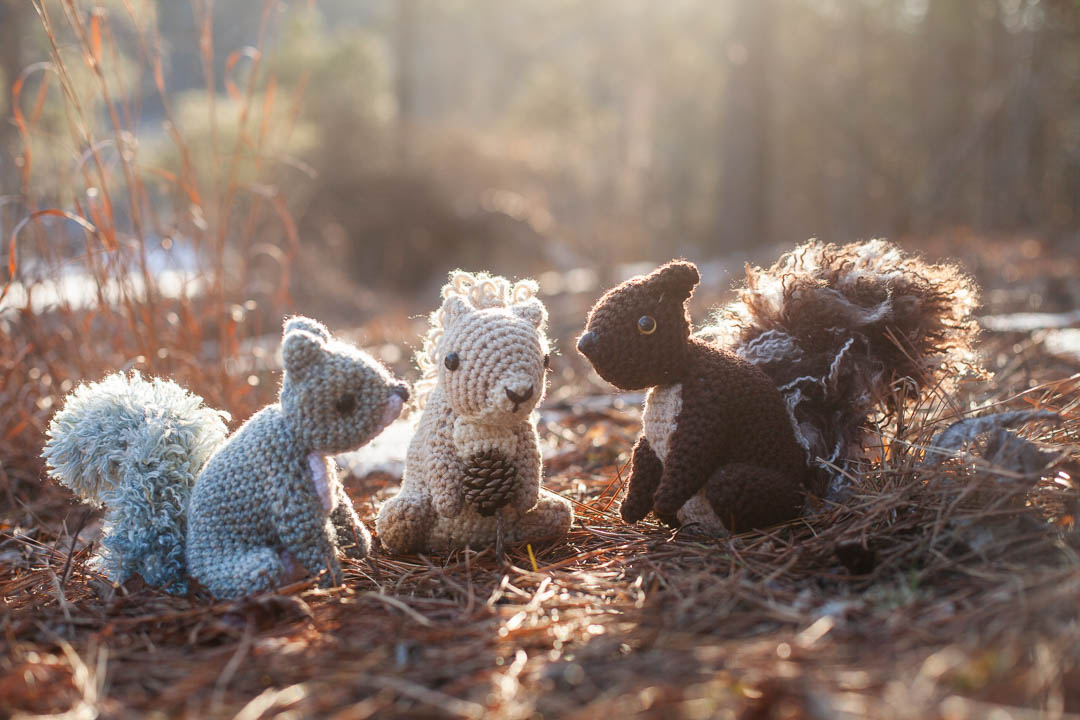 Three crochet squirrels in the forest.