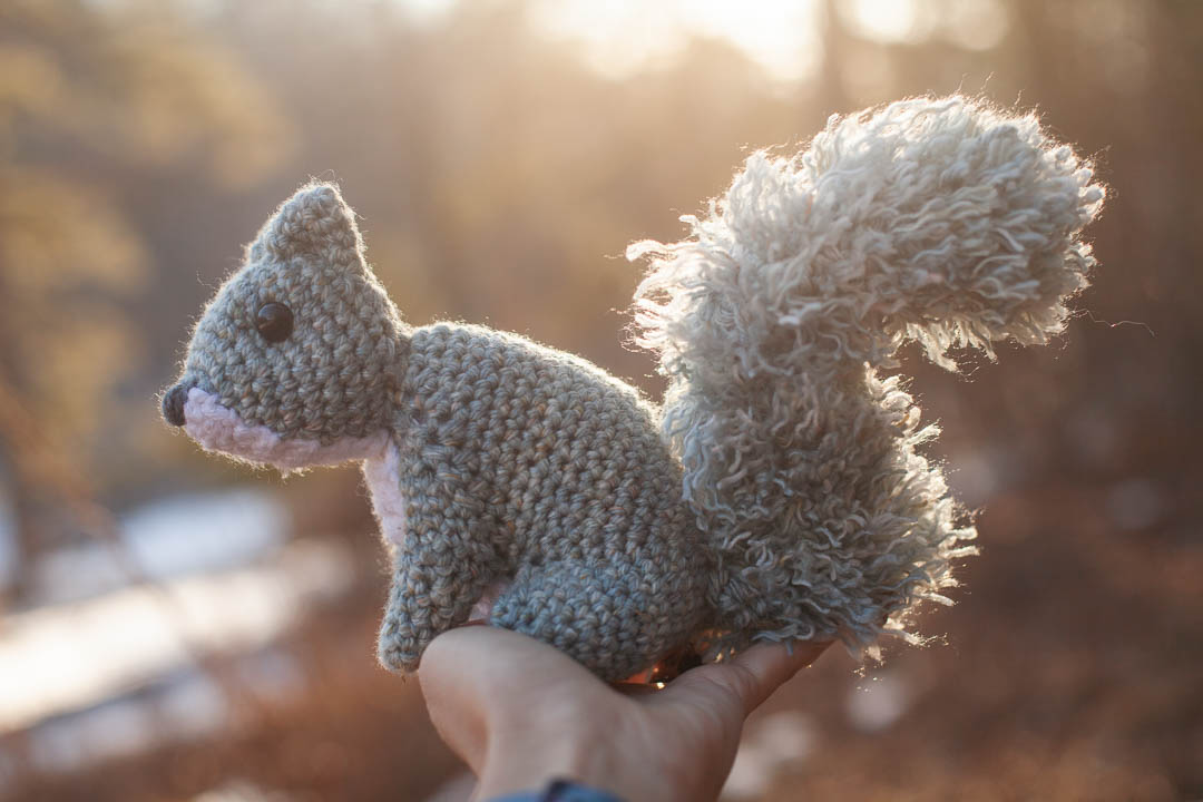 A crochet squirrel in a person's hand.