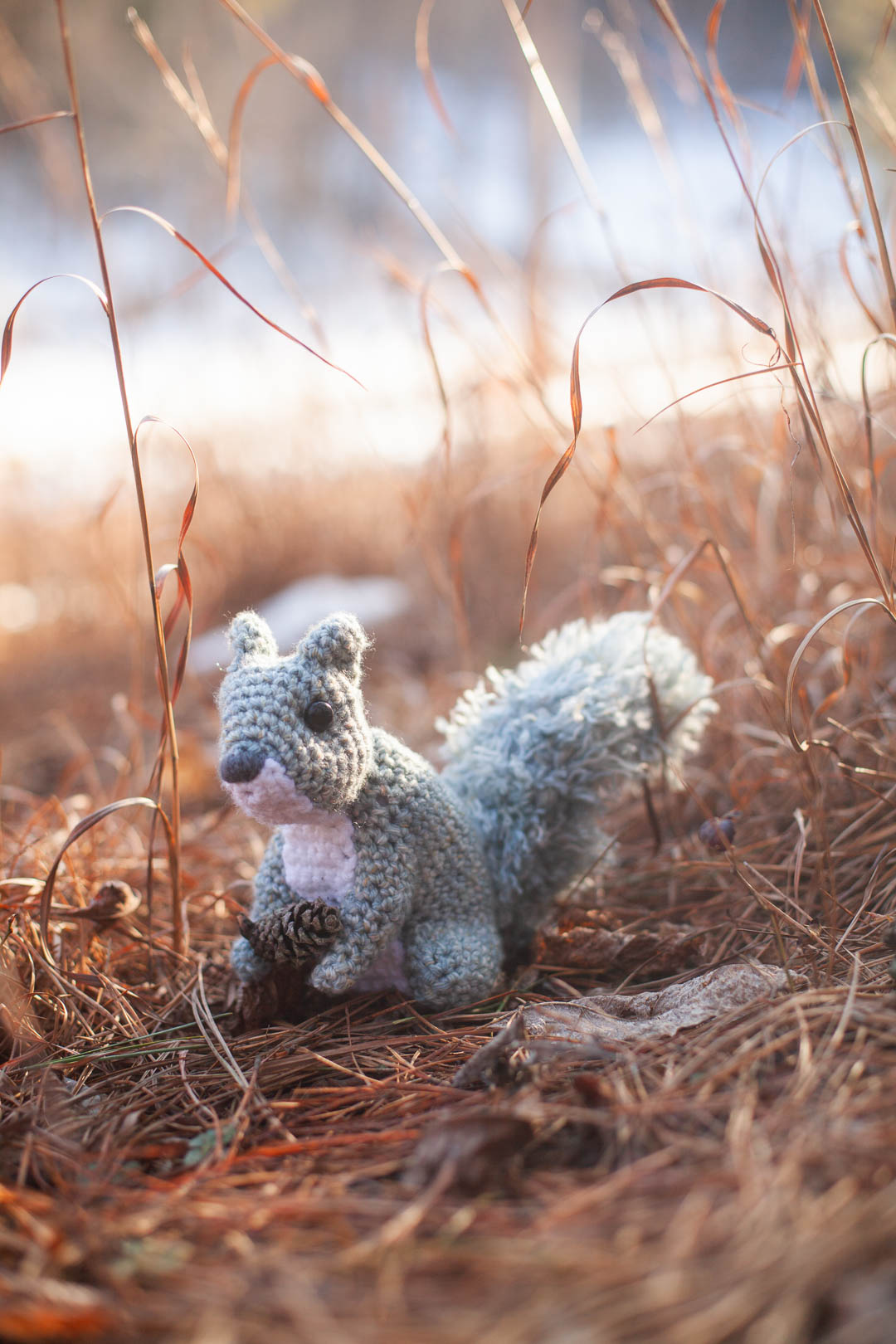 a pair of crochet pumpkins among fall leaves