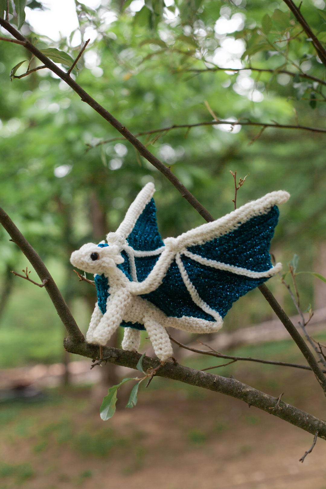 A small crochet dragon in tree branches.